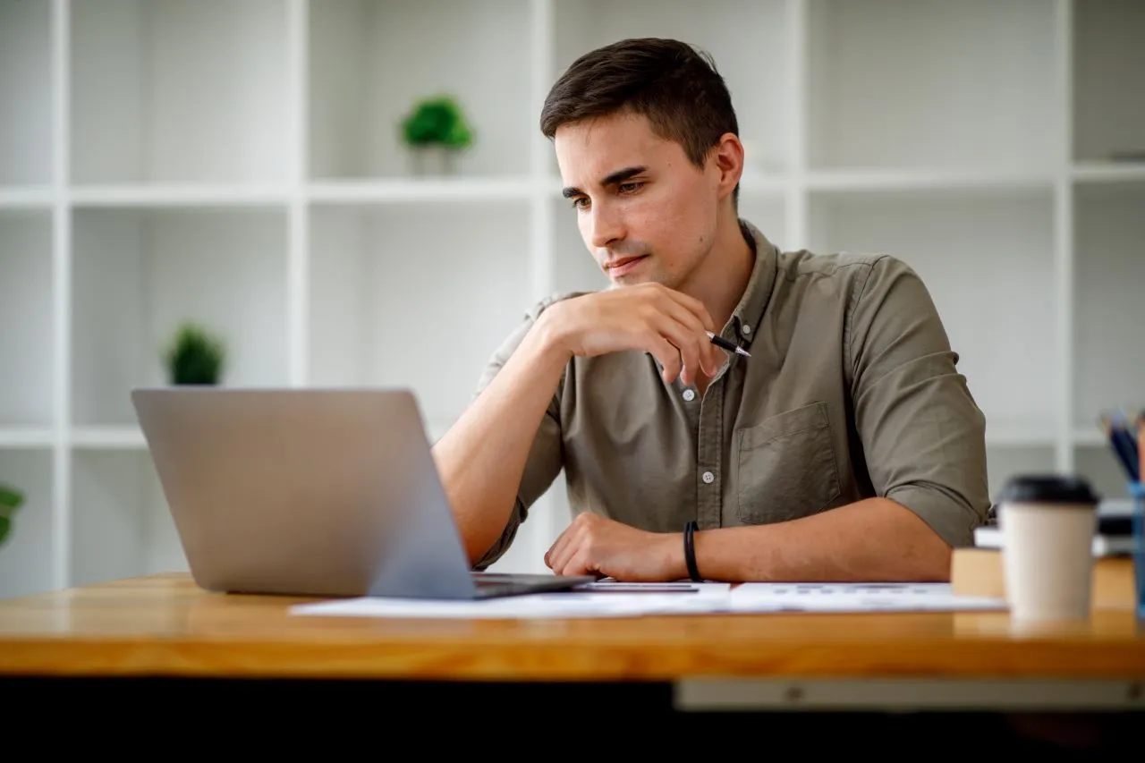 Como fazer a declaração pré-preenchida | Foto de um homem branco, cabelos castanhos, sentado numa mesa olhando para o notebook pesquisando na internet | Certificação Digital | Blog da CertiSign