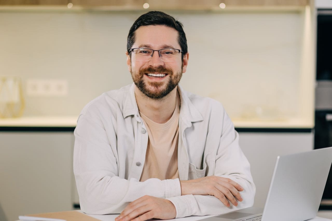 Tudo sobre o certificado digital e-CPF | Foto de um homem branco sorrindo trabalhando no escritório | Certificado Digital | Blog da Certisign