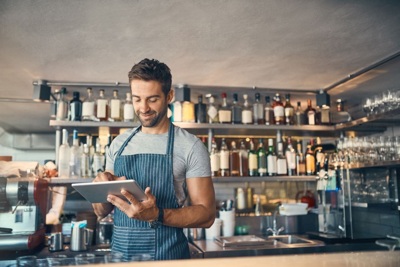 Representante legal e responsável legal de uma empresa | Foto de um rapaz trabalhando num pub com um tablet | Certificação Digital | Blog da Certisign