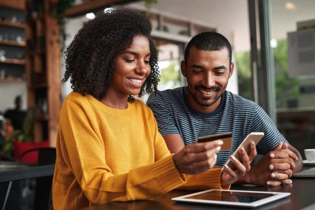 Como consultar NFC-e no site da Sefaz? | Foto de um casal consultando fazendo compra online pelo celular com cartão de crédito | Certificado Digital | Cupom Fiscal | Blog da Certisign