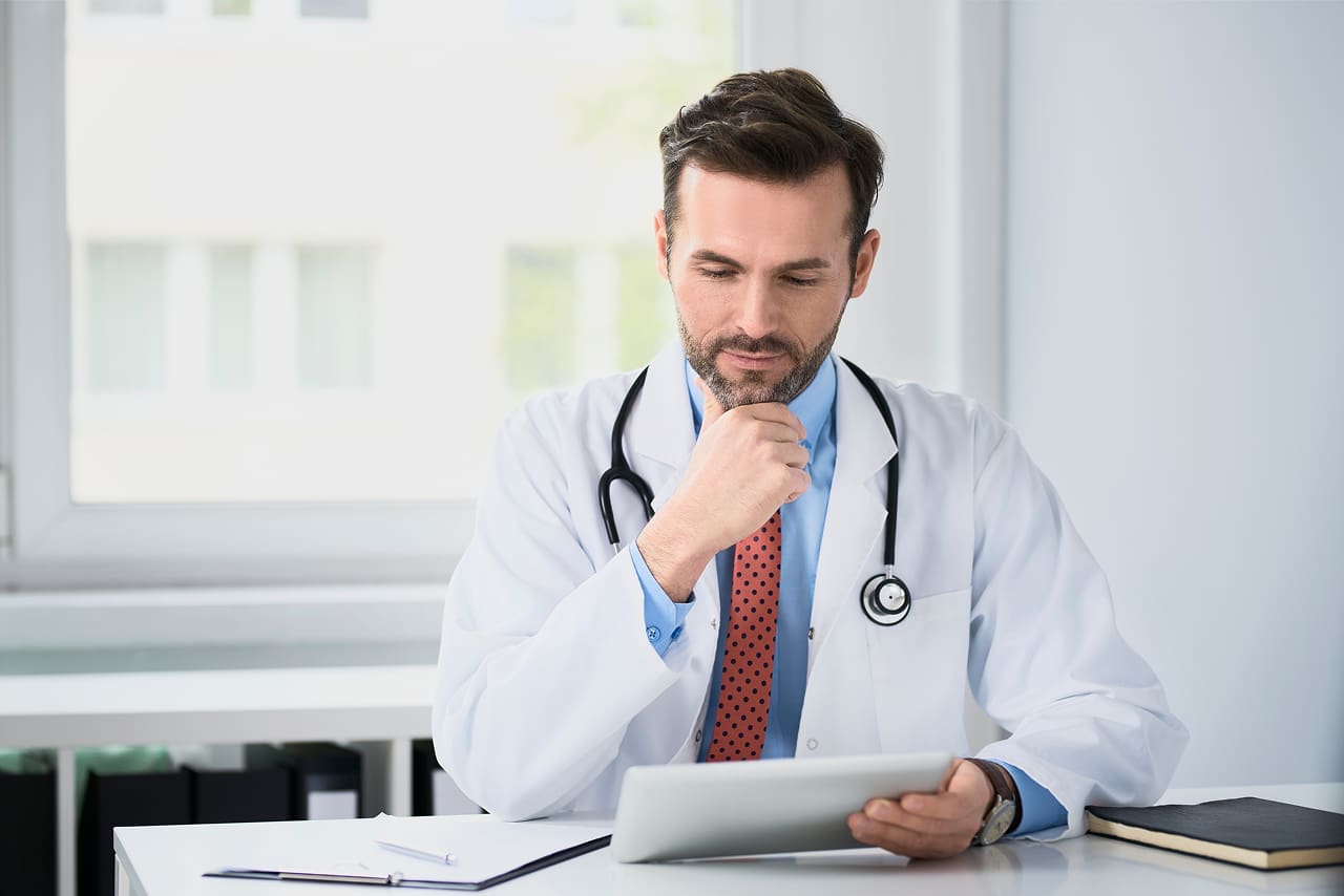  Como assinar receitas médicas eletrônicas? | Foto de um médico analisando prontuário eletrônico de paciente no tablet no consultório | Profissionais da Saúde | Assinatura Digital | Blog da Certisign