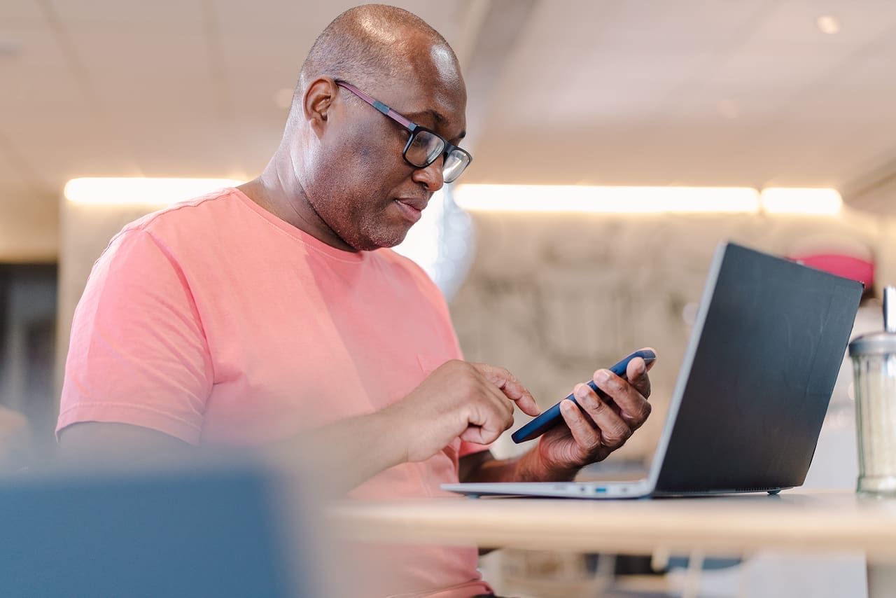 Quais obrigações acessórias exigem certificado digital? | Foto de um home negro contador olhando mensagens no celular | Certificado Digital Contabilidade | Blog da Certisign